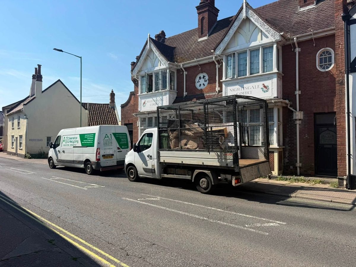 An A1 Clearance and Recycling van and a caged tipper truck parked outside a property during a clearance job in Suffolk