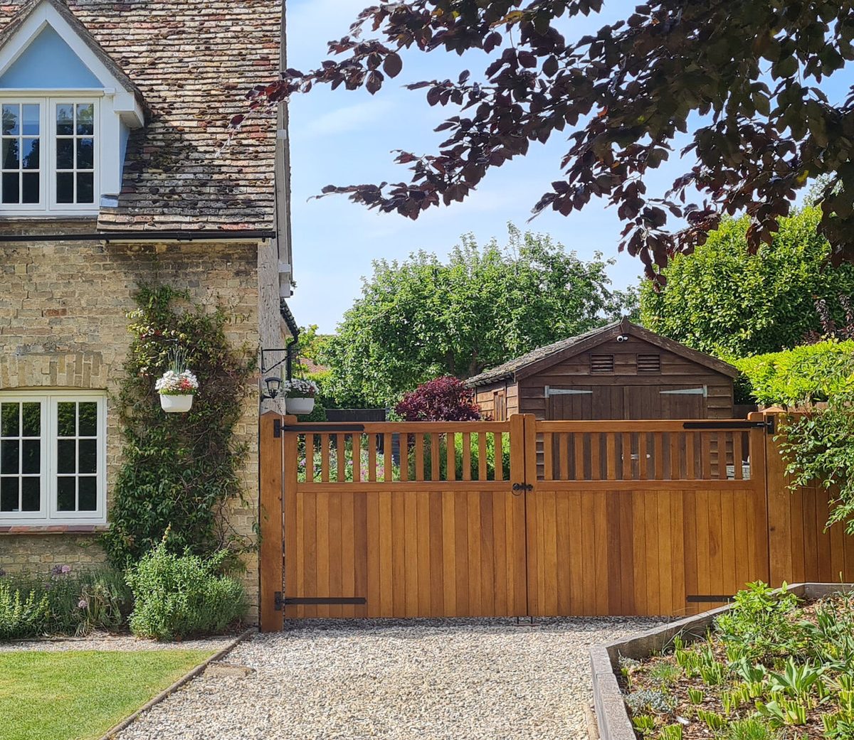 A pair of oiled iroko Cambridge style driveway gates with a matching side gate, made and installed by Countryside Gates and Fencing
