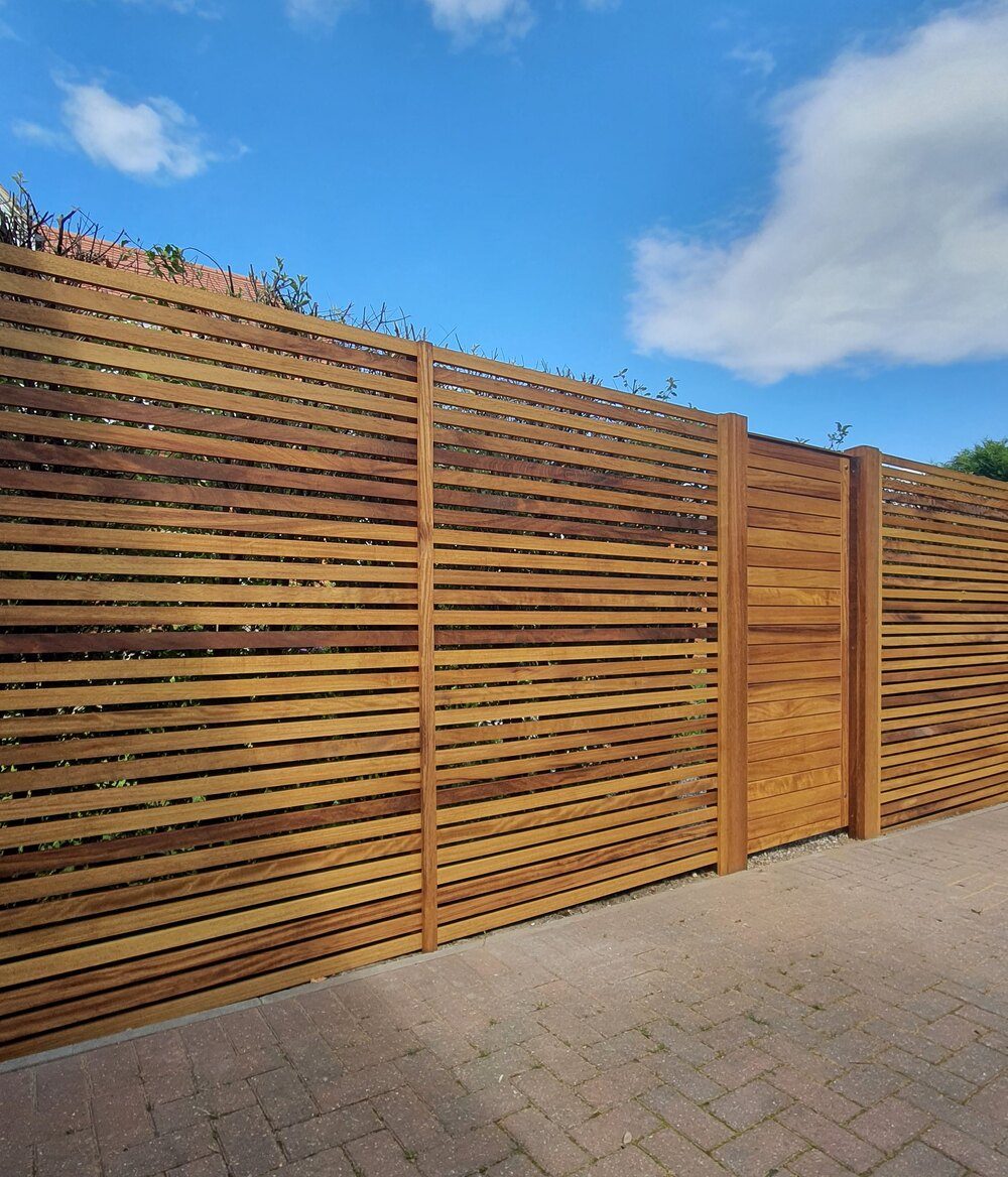 Horizontal slatted iroko fencing and matching screen panels made by Countryside Gates and Fencing
