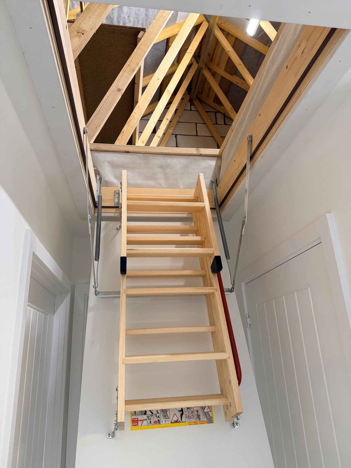 A three section wooden loft ladder installed by Earsham Lofts, lowered into a landing