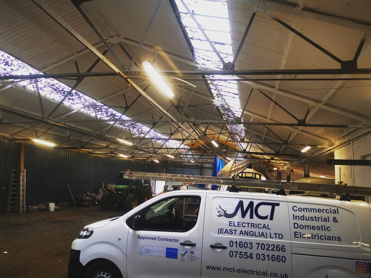 New linear lighting installed by M C T Electrical across the roof of a large agricultural workshop building, with the company van parked below