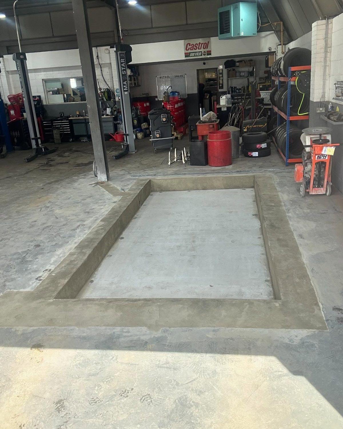 A freshly poured concrete inspection pit in a working vehicle workshop by N.B. O’Shea Construction